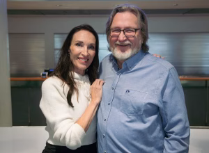 Kaksi halaavaa hymyilevää henkilöä poseeraa kameralle.