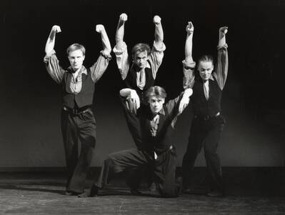 Neljä tanssijaa mustavalkoisessa kuvassa kädet ylhäällä. 