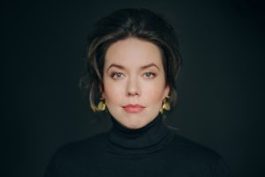 Magdalena Hinterdoblerin muotokuva. Hän katsoo suoraan kameraan, hänellä on tummat hiuset ja musta poolopaita. Tausta on musta.